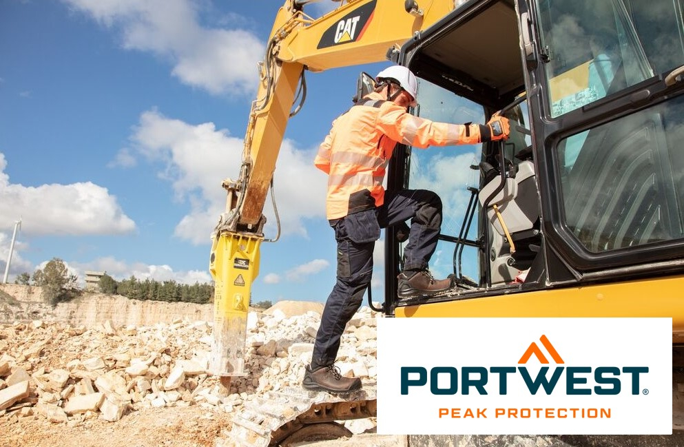 Um trabalhador com roupas de proteção laranja e capacete branco sobe na cabine de uma escavadeira amarela em um canteiro de obras. Um céu azul claro e uma pedreira podem ser vistos ao fundo. No canto inferior direito da imagem está o logotipo “Portwest Peak Protection”. Existe um link que leva à nossa seleção de luvas.